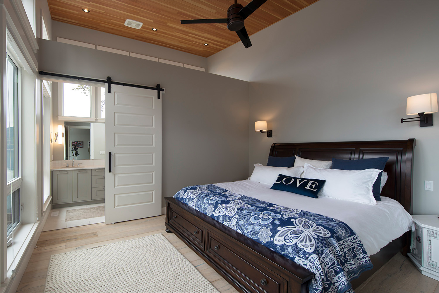 modern bedroom with king size bed, white sliding barn door and beautiful shuswap lake view