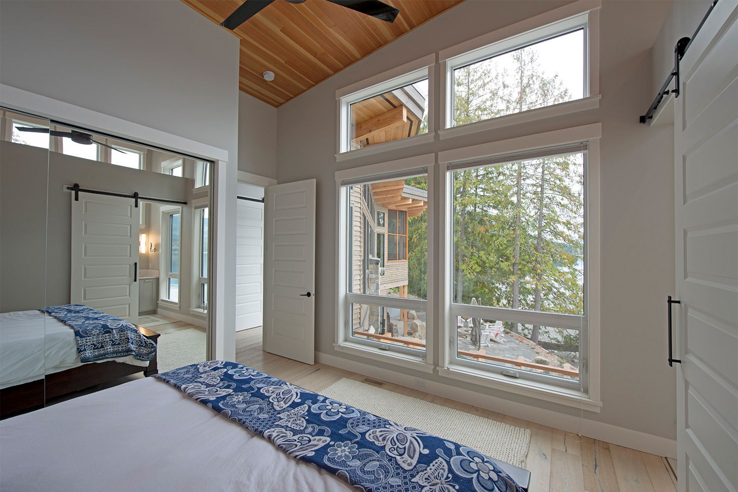 modern bedroom with closet mirror, white sliding barn door and beautiful shuswap lake view