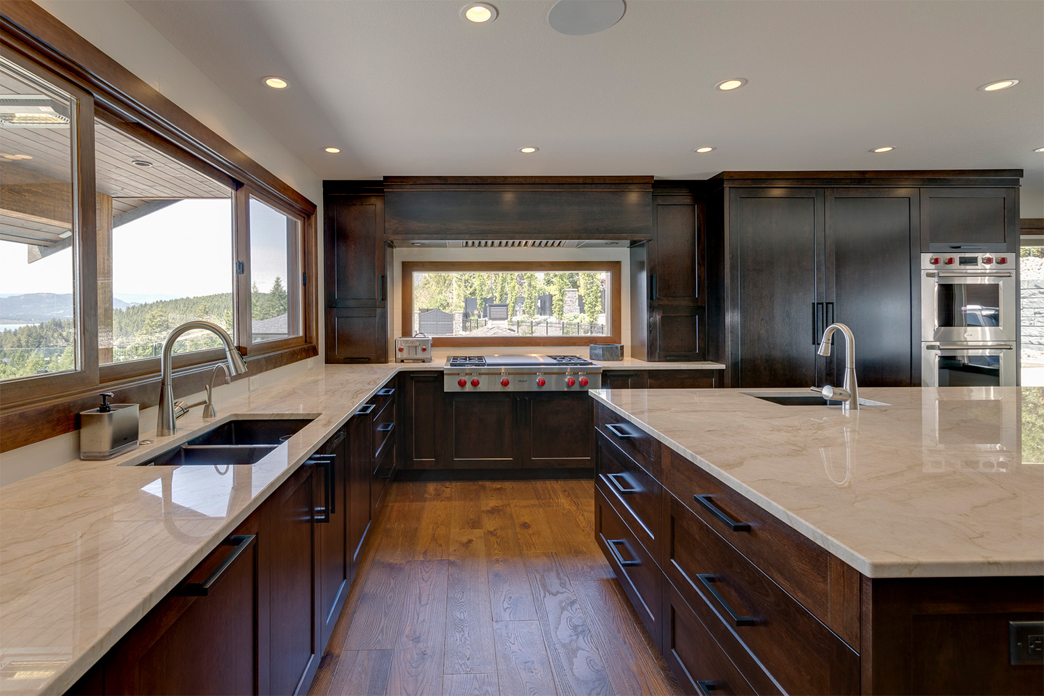 dark brown wood kitchen with large spacious marble countertops, stainless steel oven and gas stovetop