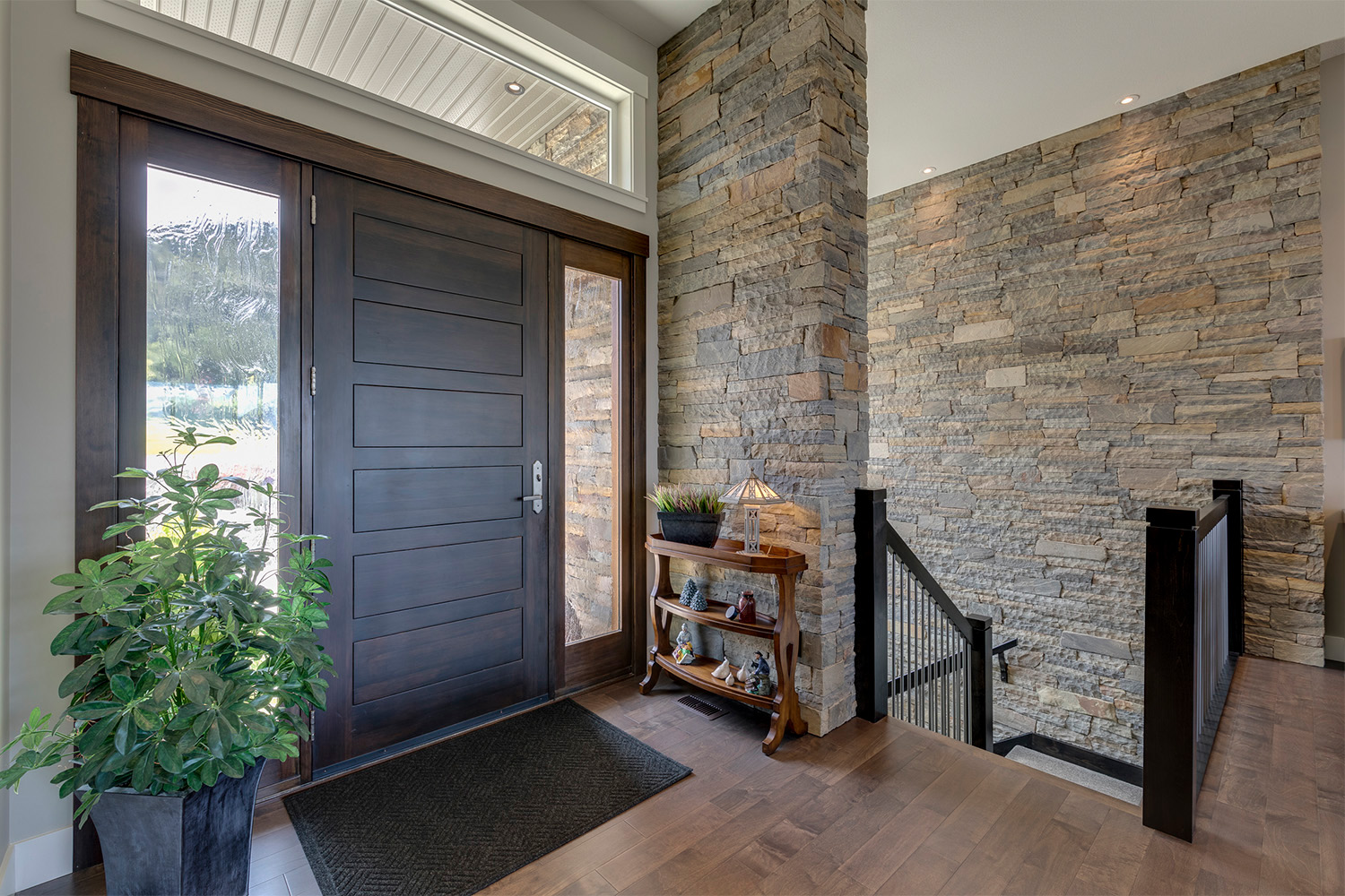 Home entry with ebony stained front door, wavy privacy glass and large multicolor rock tile walls