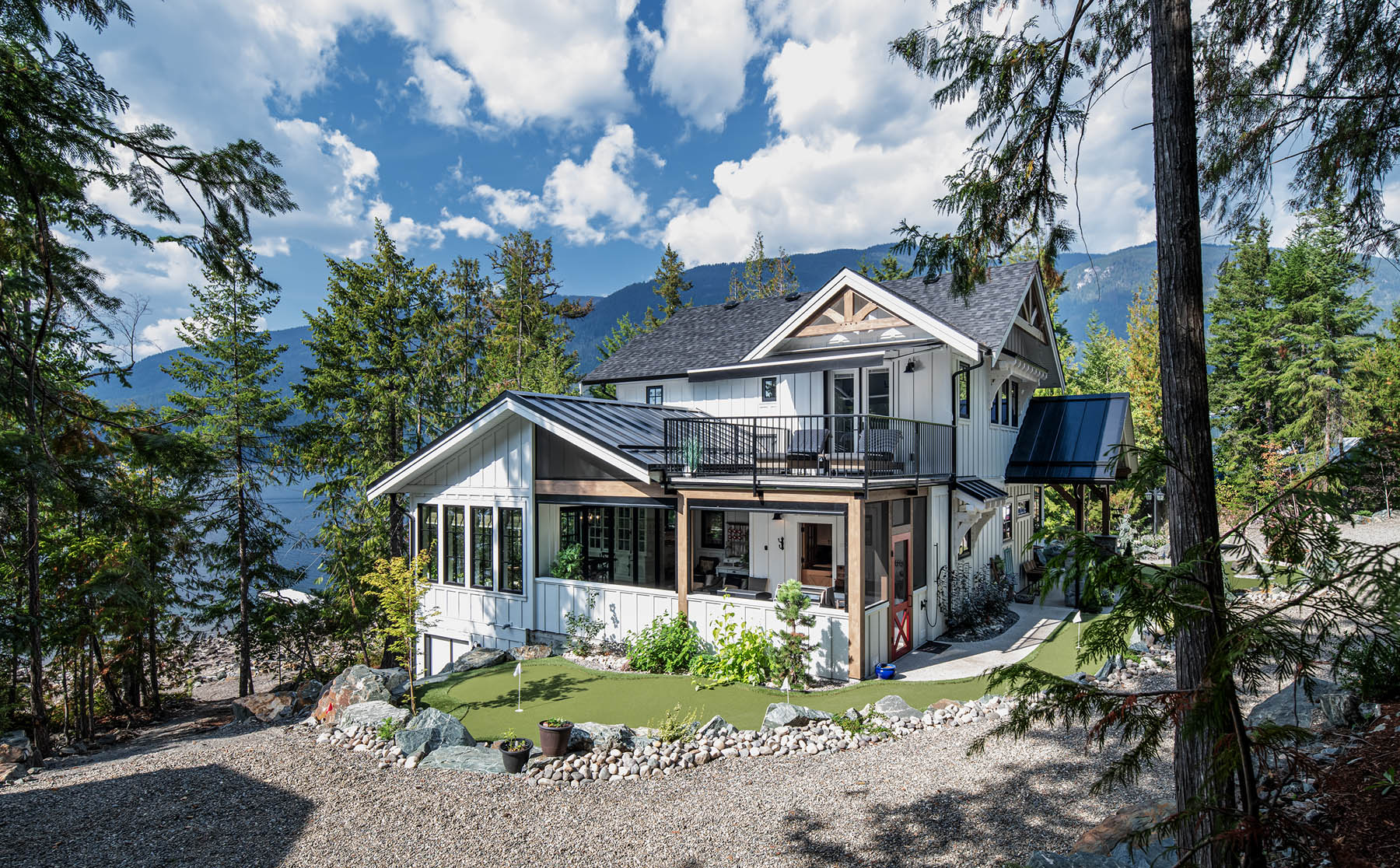 Luxurious mountain retreat home nestled among tall trees with a breathtaking view of a serene lake.